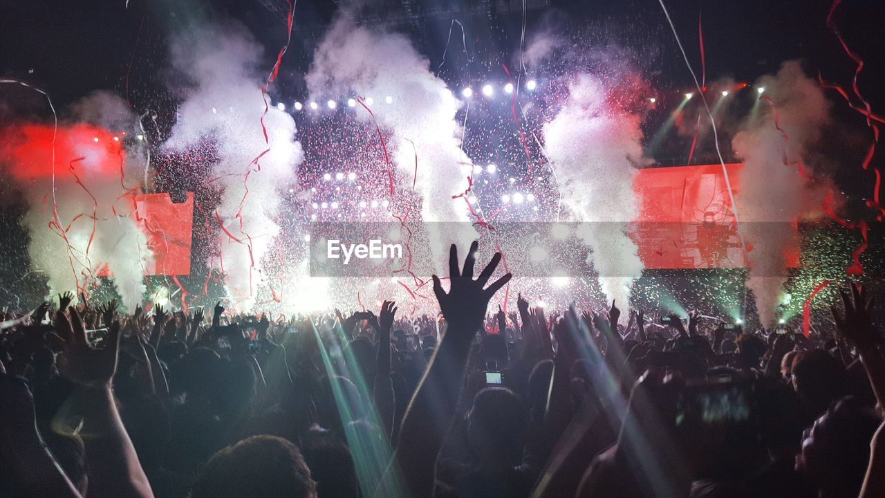 Excited fans with arms raised at concert