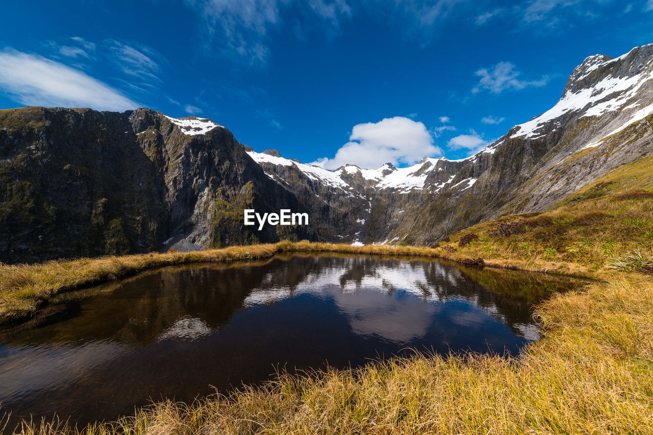 Scenic view of lake and mountains against blue sky