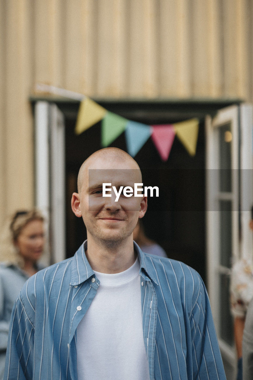 Portrait of smiling young man with shaved head during dinner party at cafe