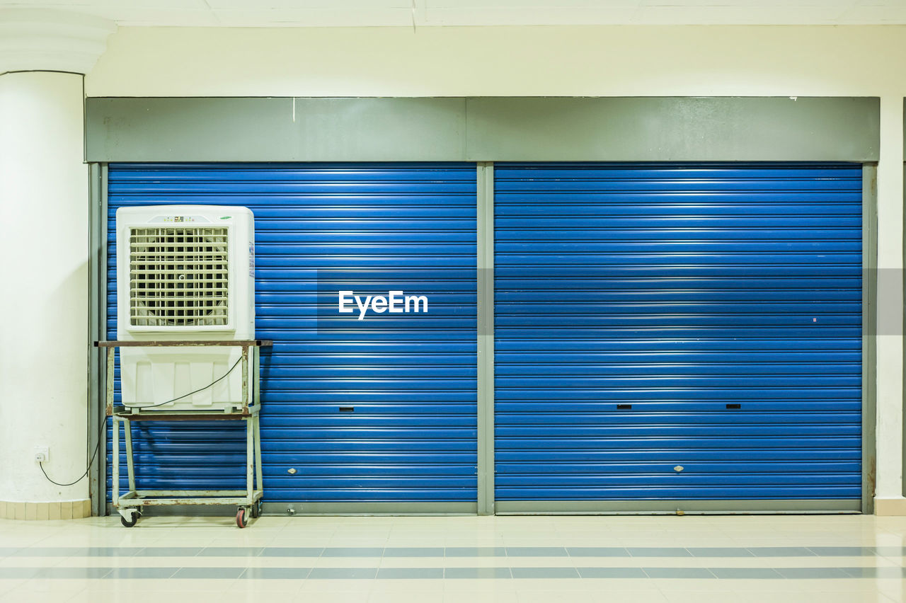 Air conditioner on trolley against closed blue shutters