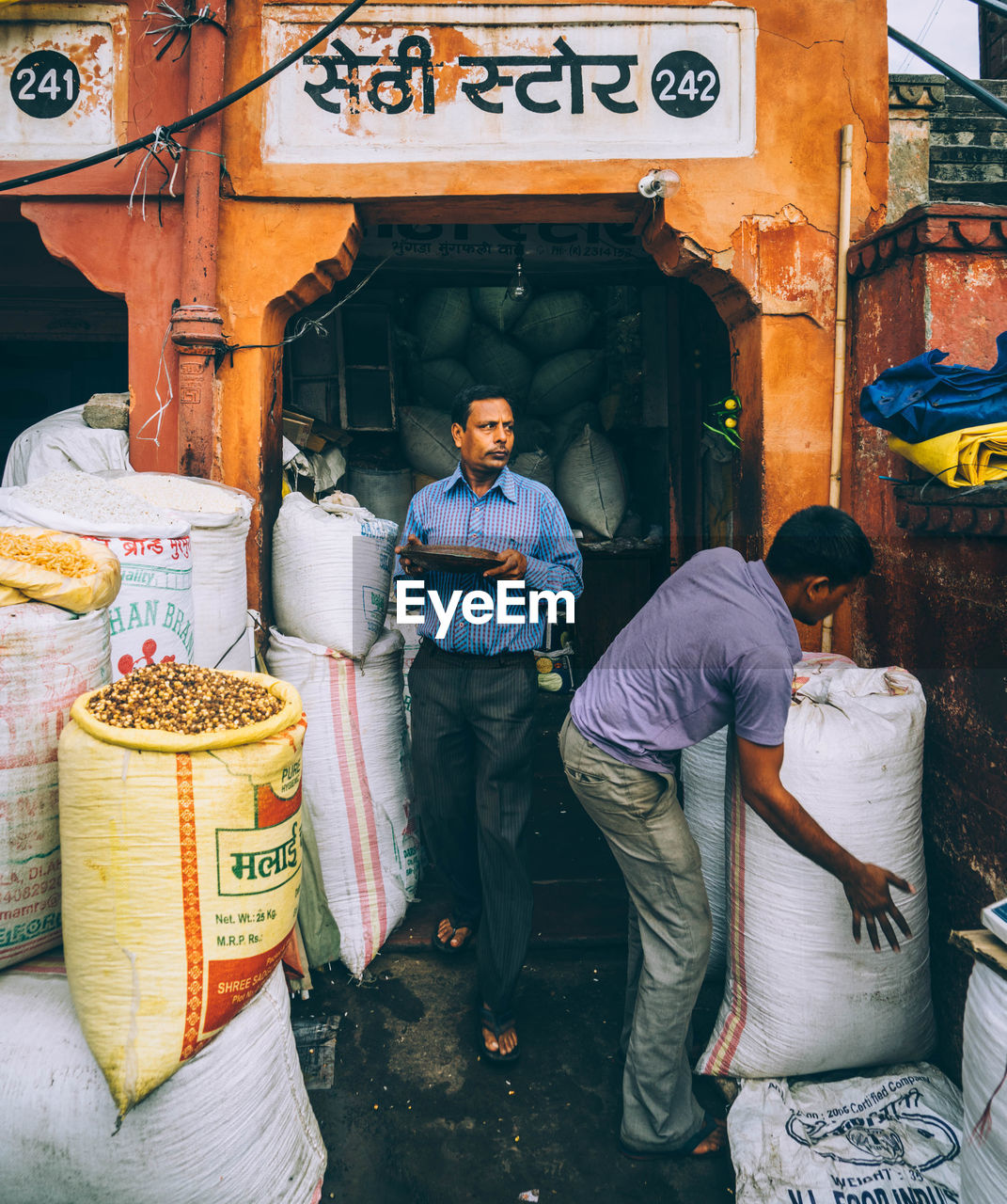 WOMAN STANDING IN FRONT OF SHOP IN MARKET