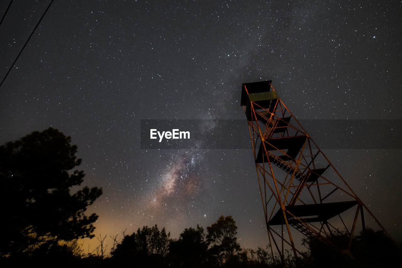 Low angle view of communications tower against sky at night