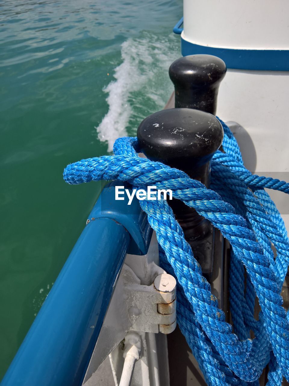 HIGH ANGLE VIEW OF ROPE TIED TO BOAT MOORED AT HARBOR