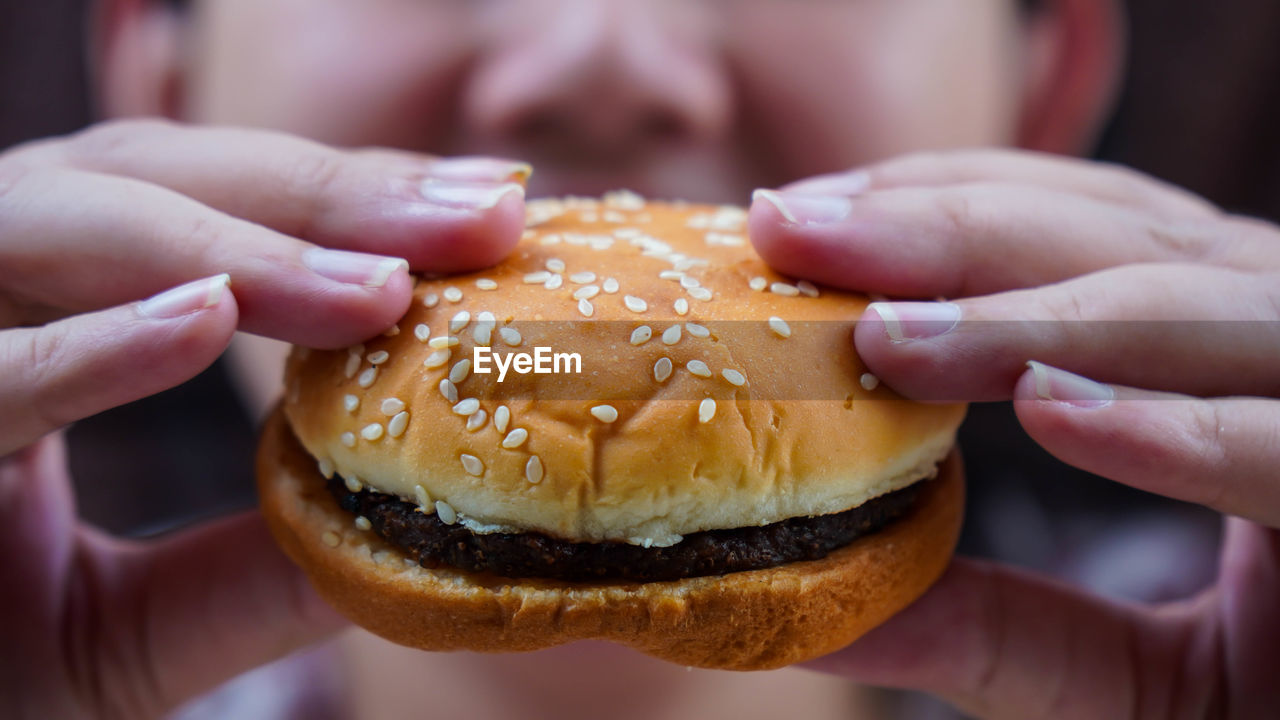 Midsection of person holding beef burger