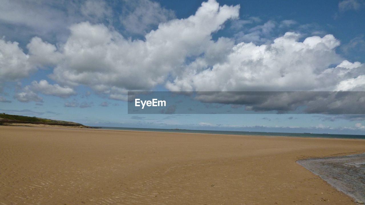 Scenic view of beach against cloudy sky