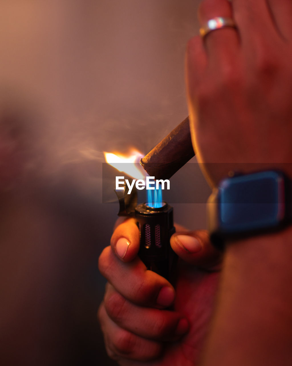 Cropped hand holding a torch lighter lighting a cigar