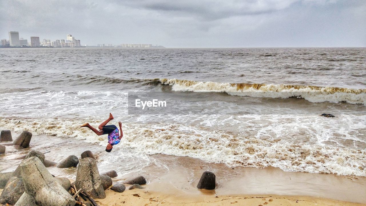 Full length of boy backflipping at beach