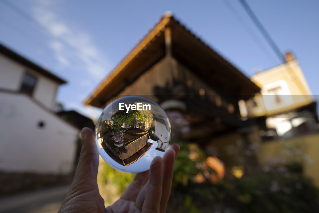 Horreo, raised granary, is reflected over a glass ball