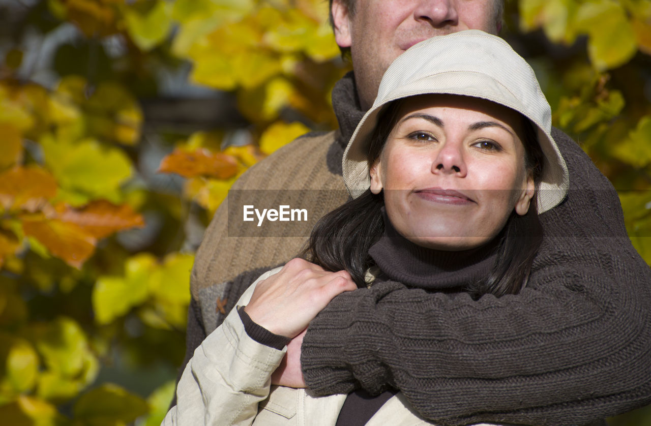 Midsection of man embracing girlfriend at park during autumn