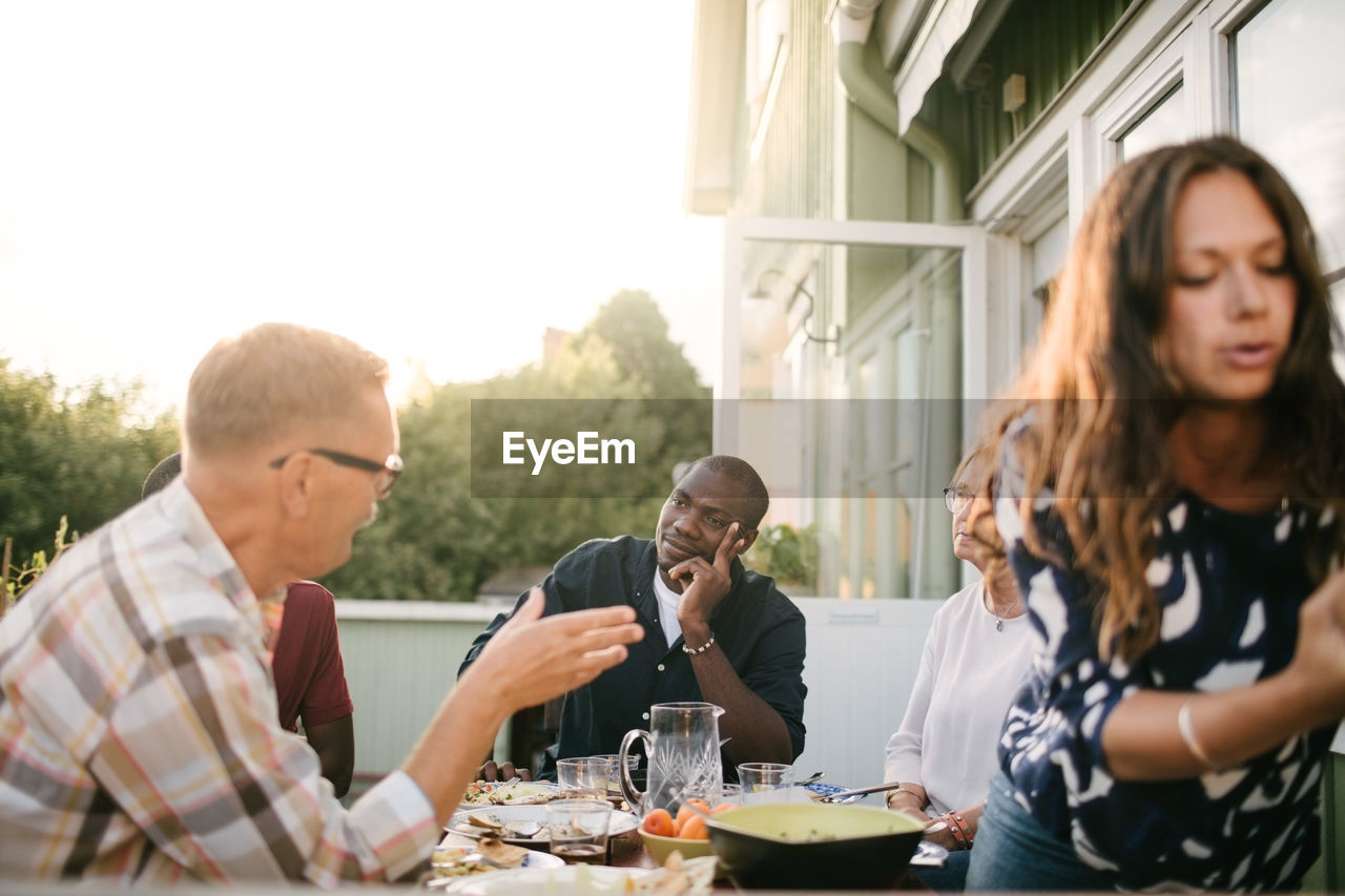 Multi-generation family talking while having lunch at table on porch