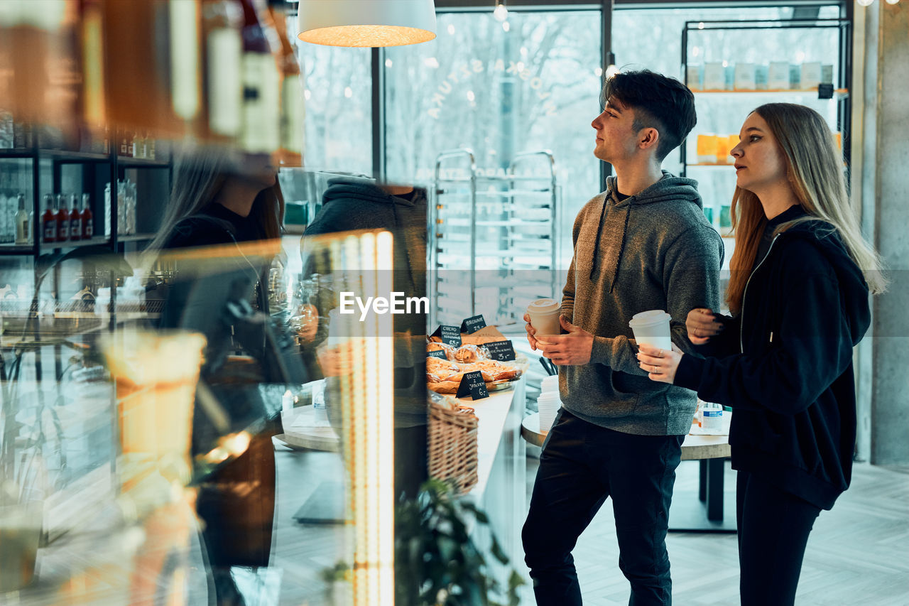 Friends doing shopping in a coffee shop.. people buying coffee and sweet snacks to go