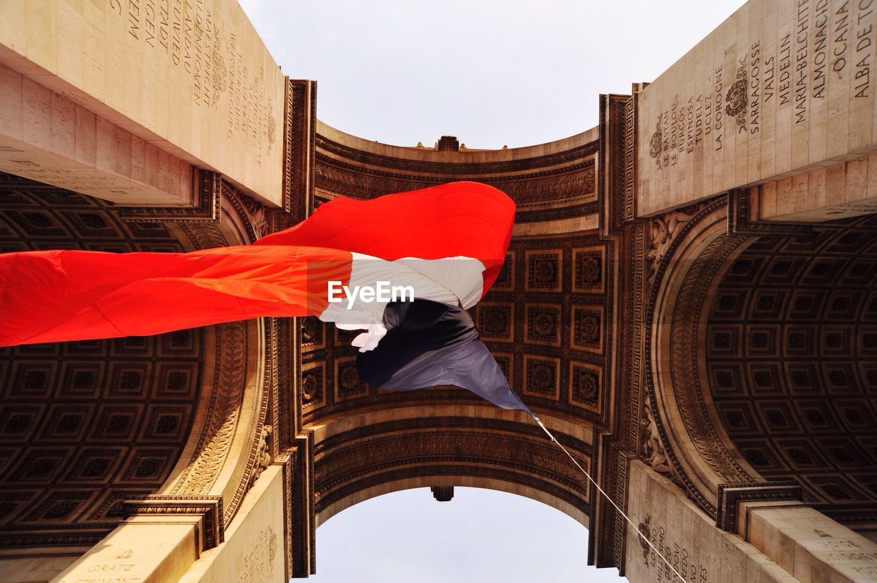 Directly below shot of french flag waving below arc de triomphe