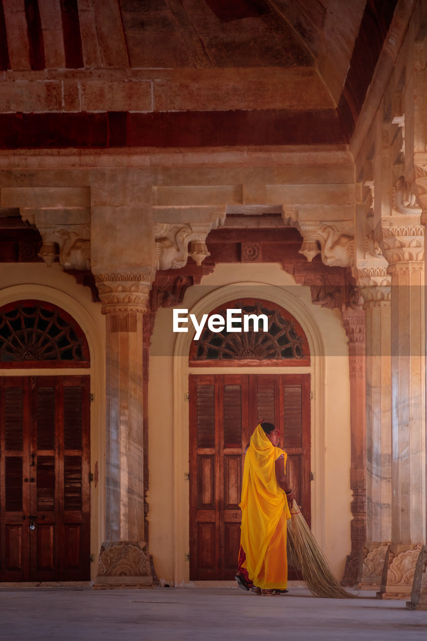 REAR VIEW OF MAN WALKING IN TEMPLE