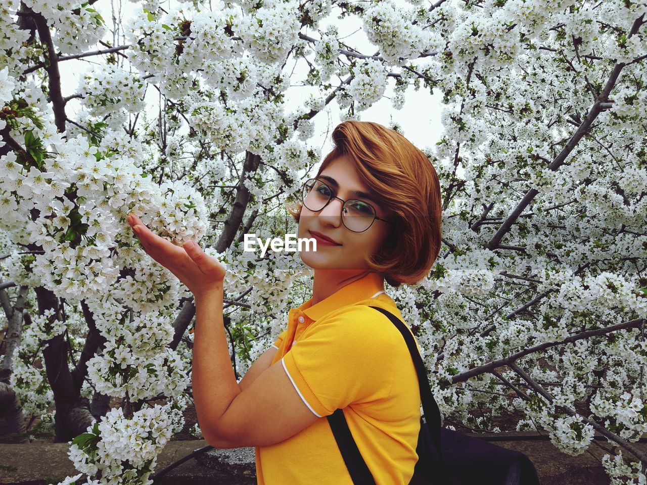 Portrait of smiling young woman standing against trees