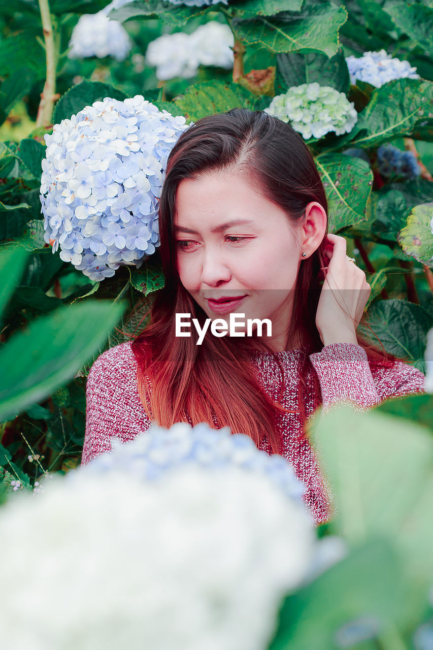 Mid adult woman by flowering plants in park