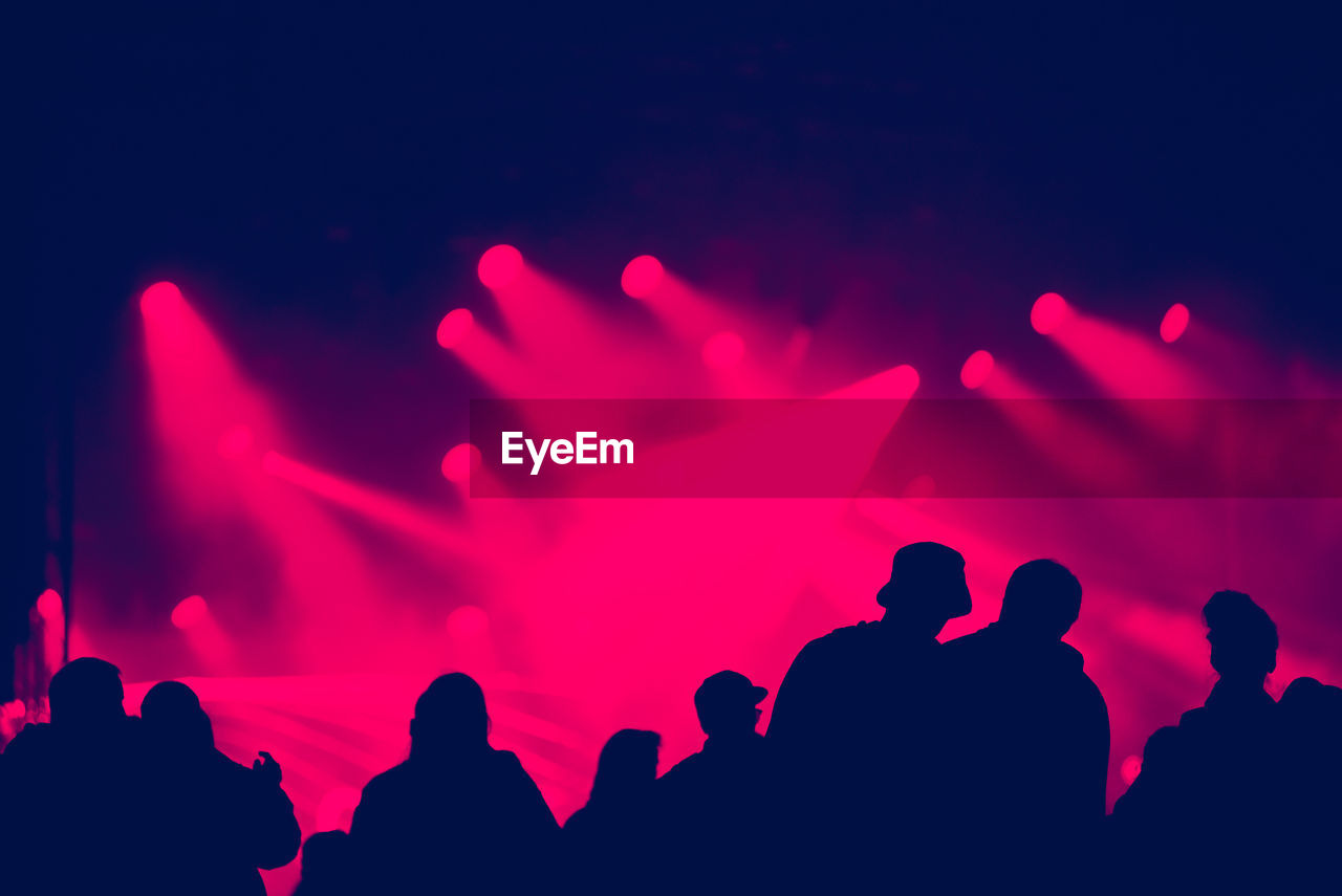 Silhouette of cheering crowd at a concert. colorful bright stage lights in the background