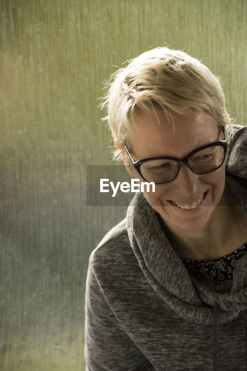 CLOSE-UP PORTRAIT OF A SMILING YOUNG WOMAN WITH EYEGLASSES