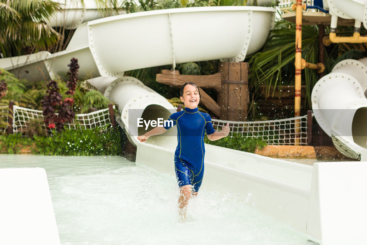 Happy girl running in water at water park