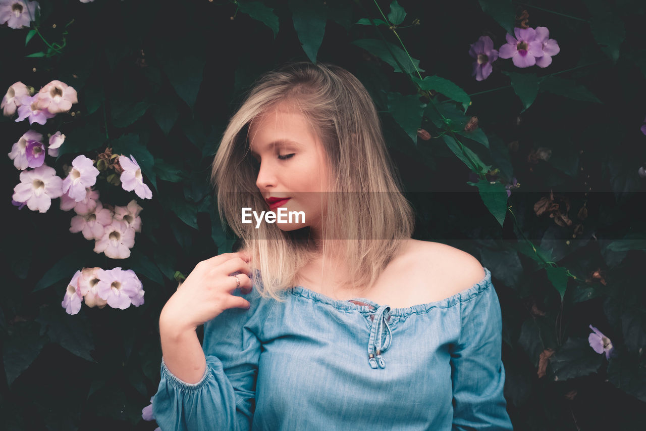 Young woman with eyes closed by plants