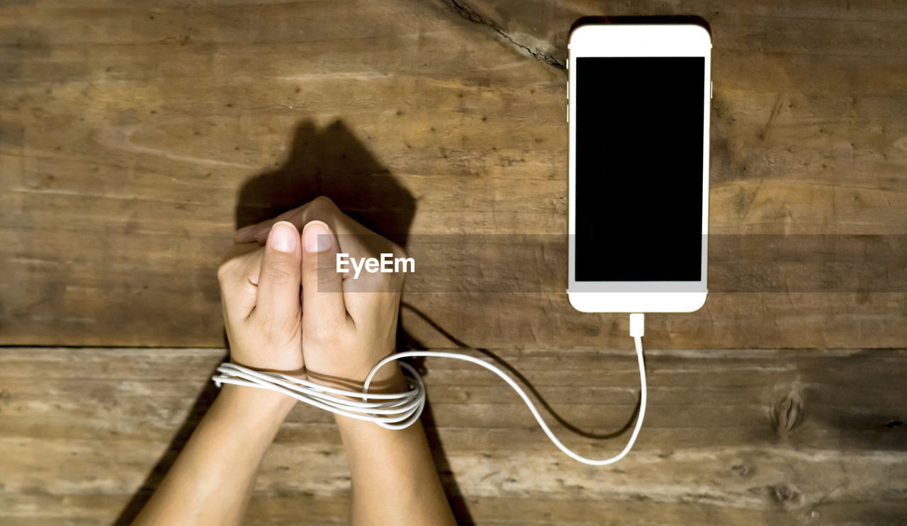 Cropped image of woman hands tied with usb cable at table