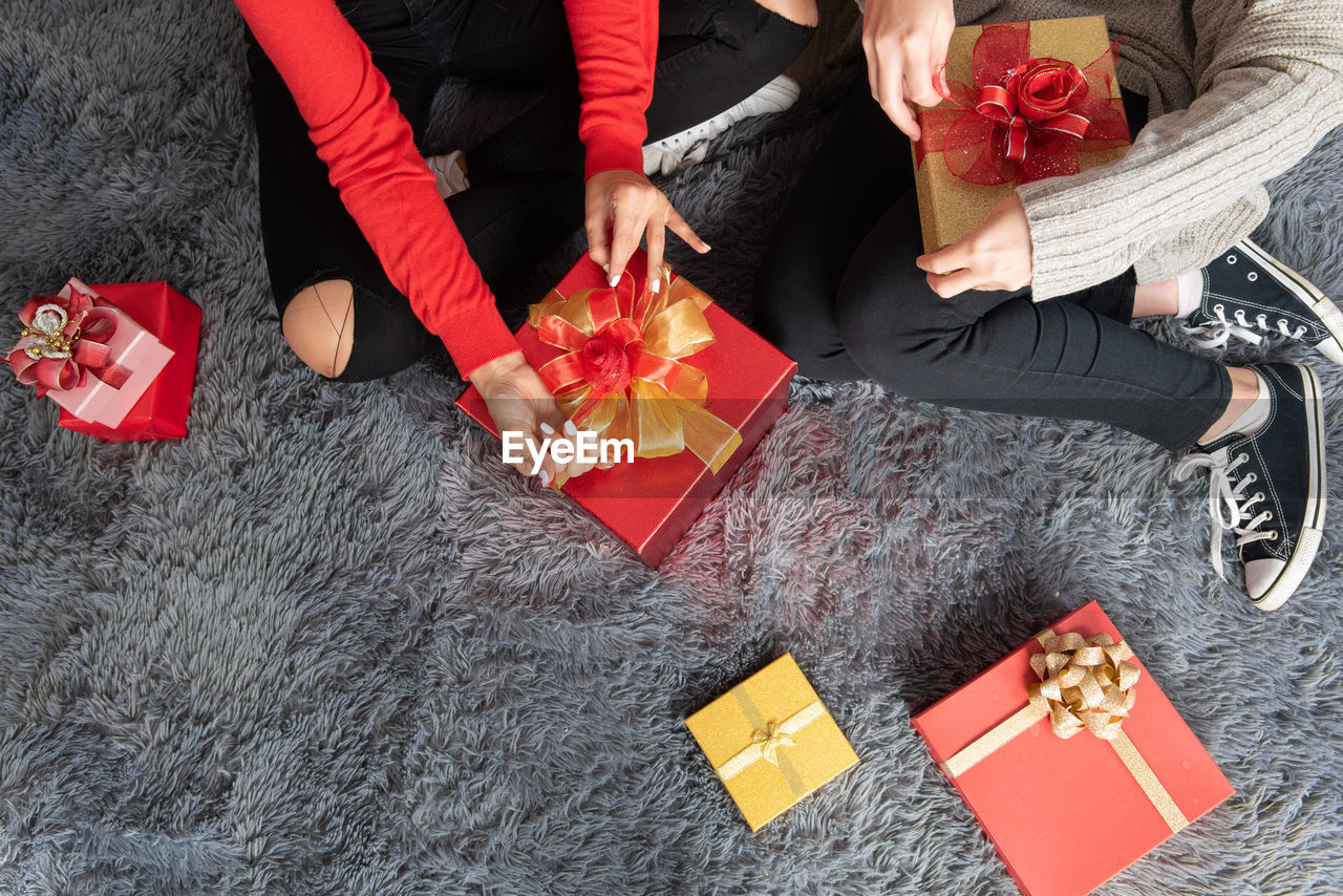 Top view of two women hands sitting making gift boxes to celebrate christmas and new year 