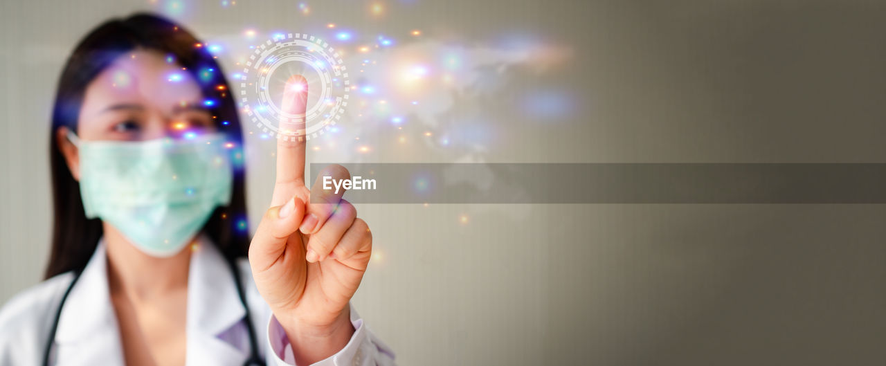 Selective focus of index finger of asian woman doctor in a doctor suit on white background