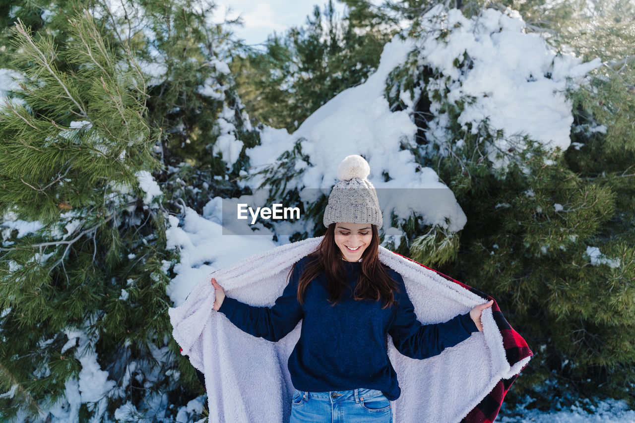 Woman wearing warm clothing against trees during winter