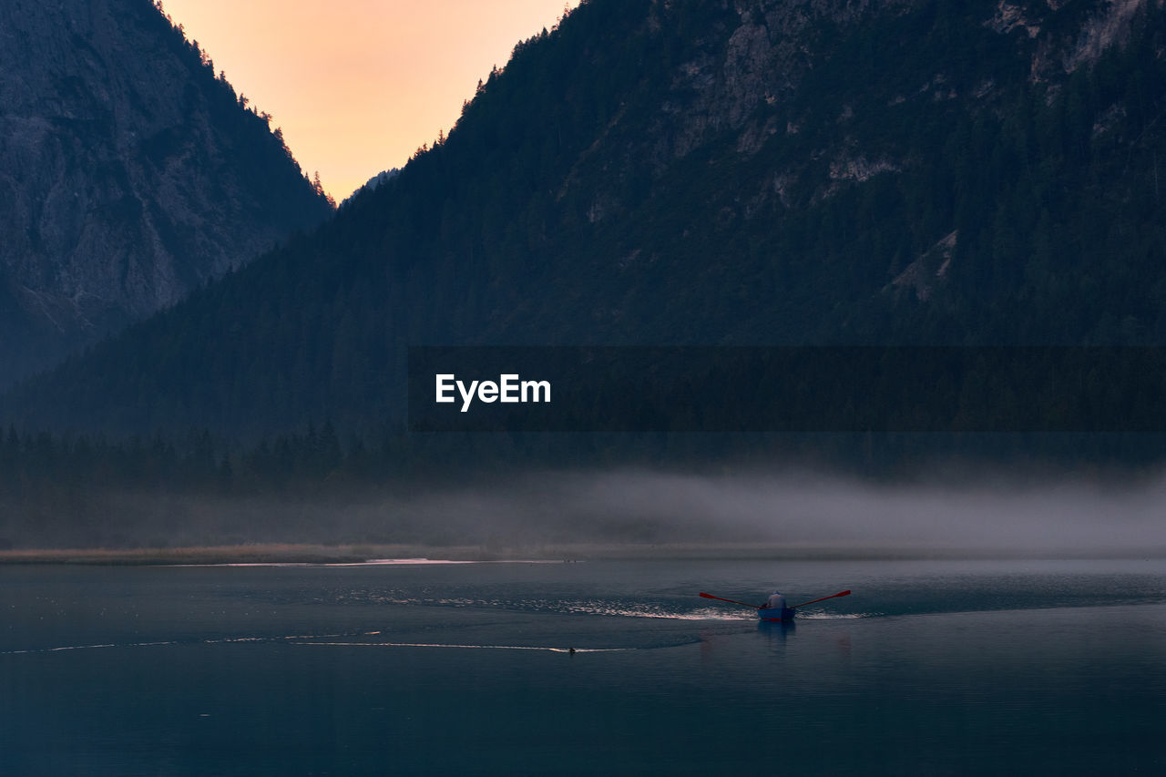 Scenic view of sea by mountain against sky