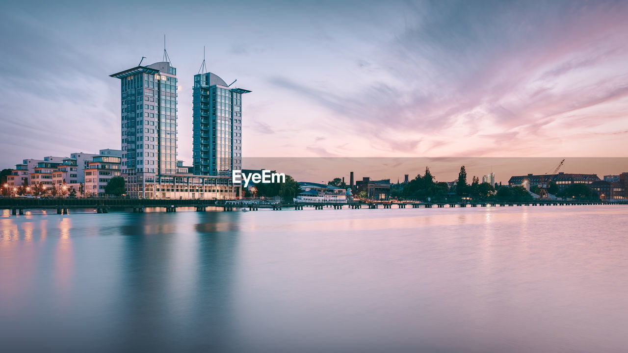 Twintowers berlin by spree river against sky during sunset