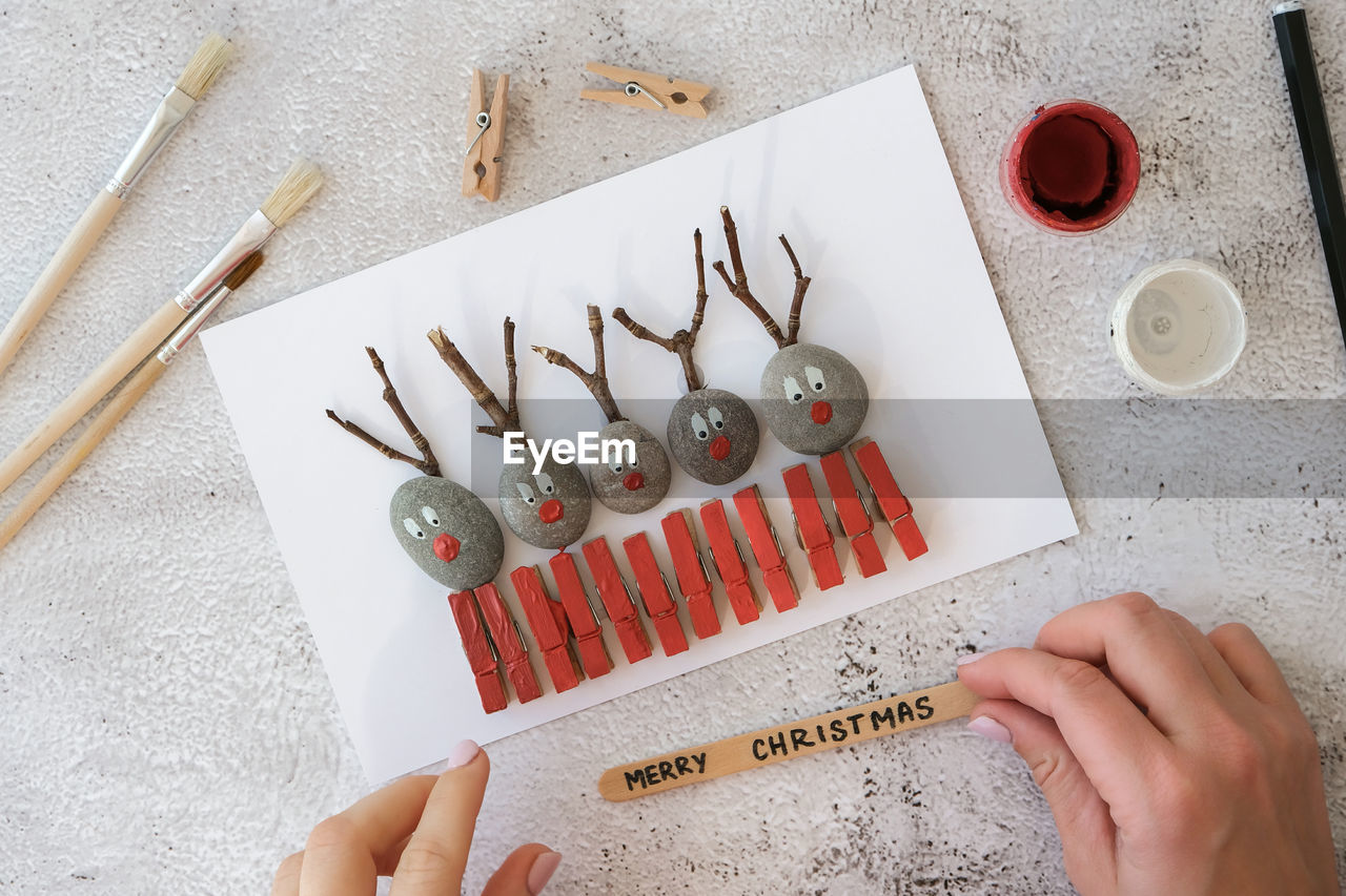 Diy merry christmas deer on greeting card postcard made of pebbles, sea stones, clothespins 