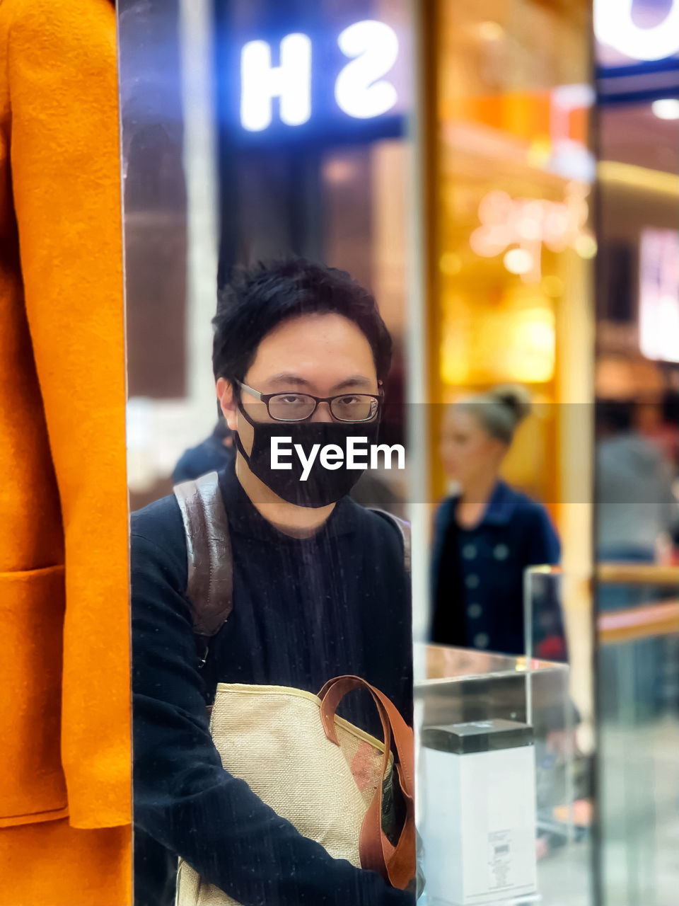 Portrait of young man reflected in mirror at shopping mall.