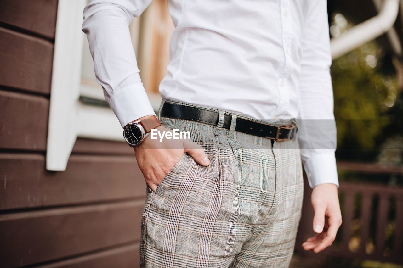 Midsection of well-dressed man standing in park