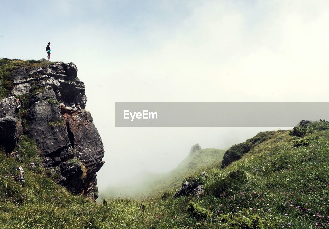 Woman standing on cliff during foggy weather