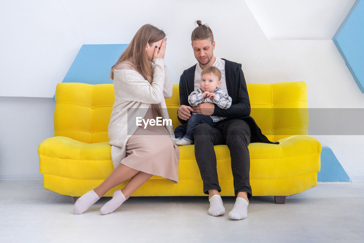 Man and woman sitting with son on sofa at home