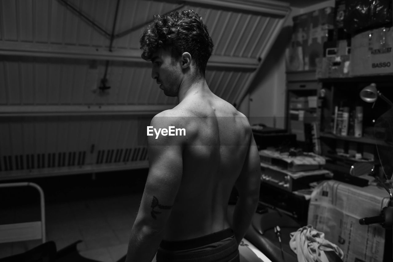 Shirtless man standing in workshop