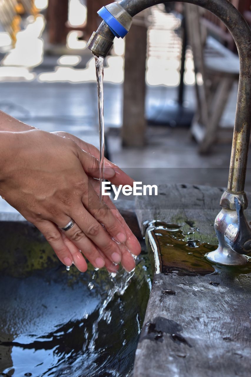 Person washing hands from faucet