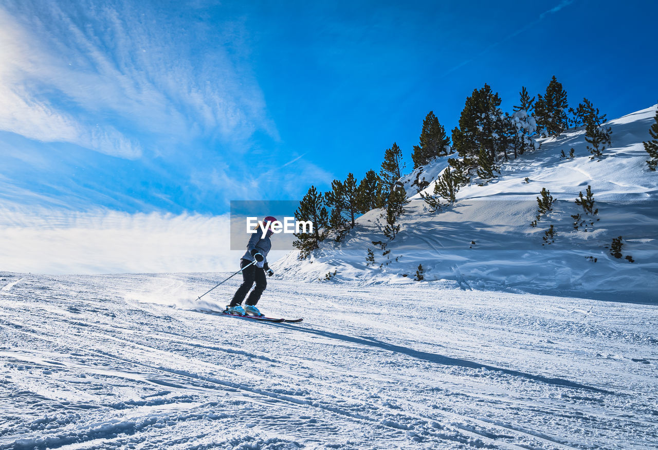 snow, winter, cold temperature, sports, mountain, winter sports, leisure activity, skiing, nature, mountain range, vacation, sky, holiday, one person, adventure, trip, full length, landscape, environment, ski holiday, ski, scenics - nature, extreme sports, beauty in nature, travel, day, ski equipment, piste, sunlight, motion, footwear, travel destinations, adult, activity, ski touring, sports equipment, land, ski mountaineering, lifestyles, tree, blue, clothing, white, men, ski-wear, snowboarding, non-urban scene, recreation, nordic skiing, outdoors, downhill, cloud, plant, ski pole, snowcapped mountain, side view, tourism