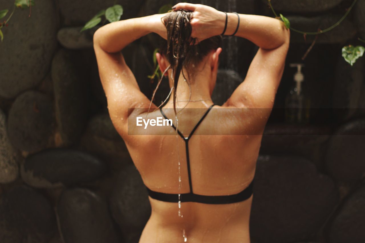 Rear view of woman in bikini top taking shower