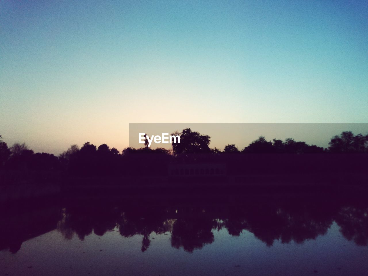 SCENIC VIEW OF CALM LAKE AT SUNSET