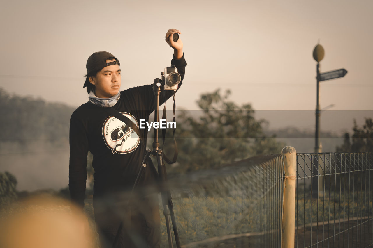 MAN STANDING AGAINST SKY DURING SUNSET