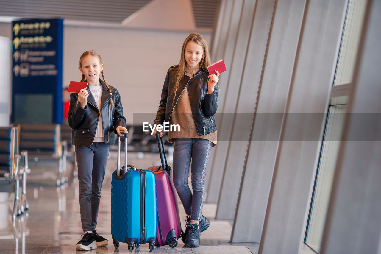 Sisters holding passport while standing at airport