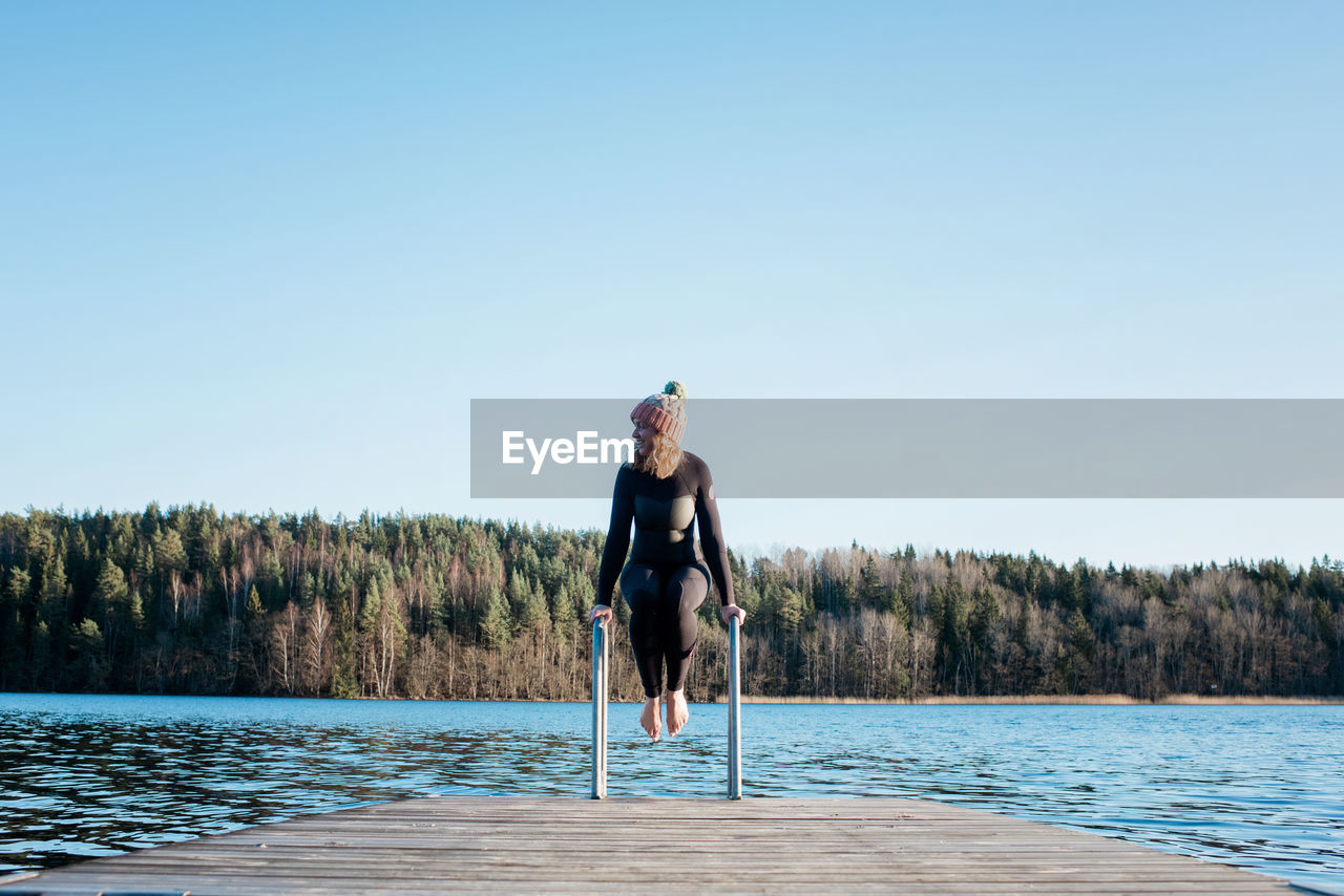 Woman about to jump into cold ice water whilst at the beach in sweden