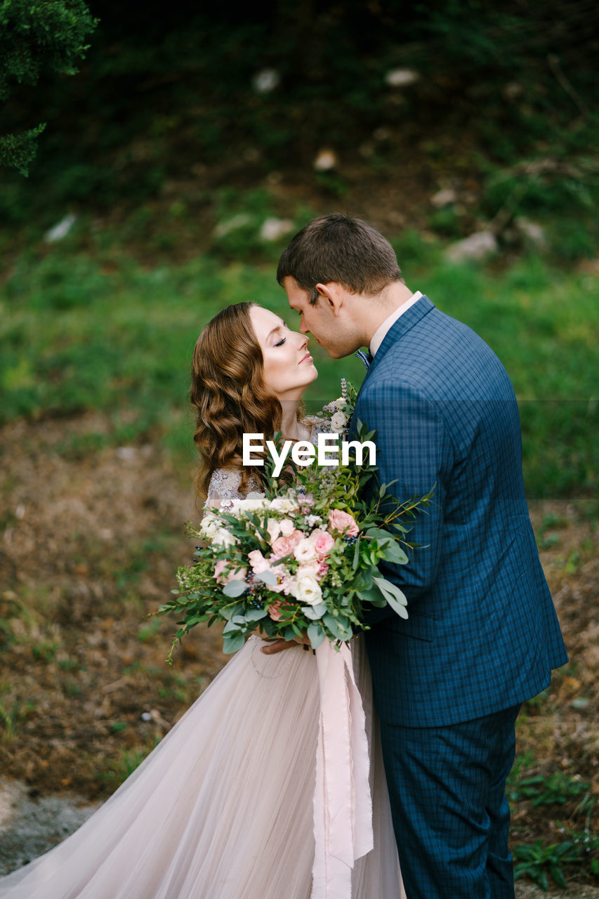 REAR VIEW OF MAN AND WOMAN HOLDING BOUQUET