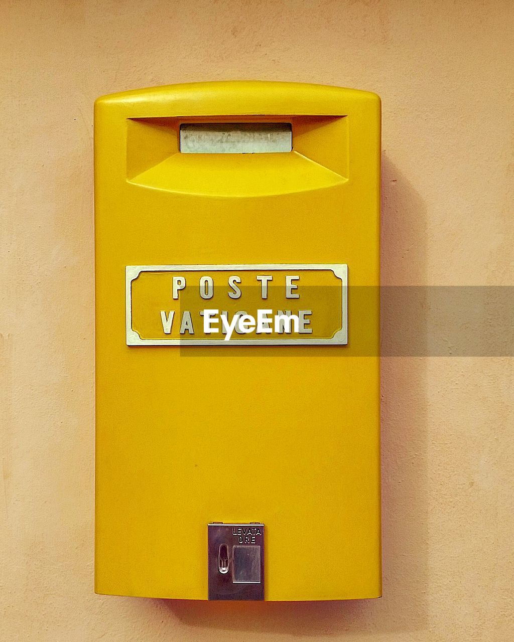 Close-up of yellow public mailbox on wall