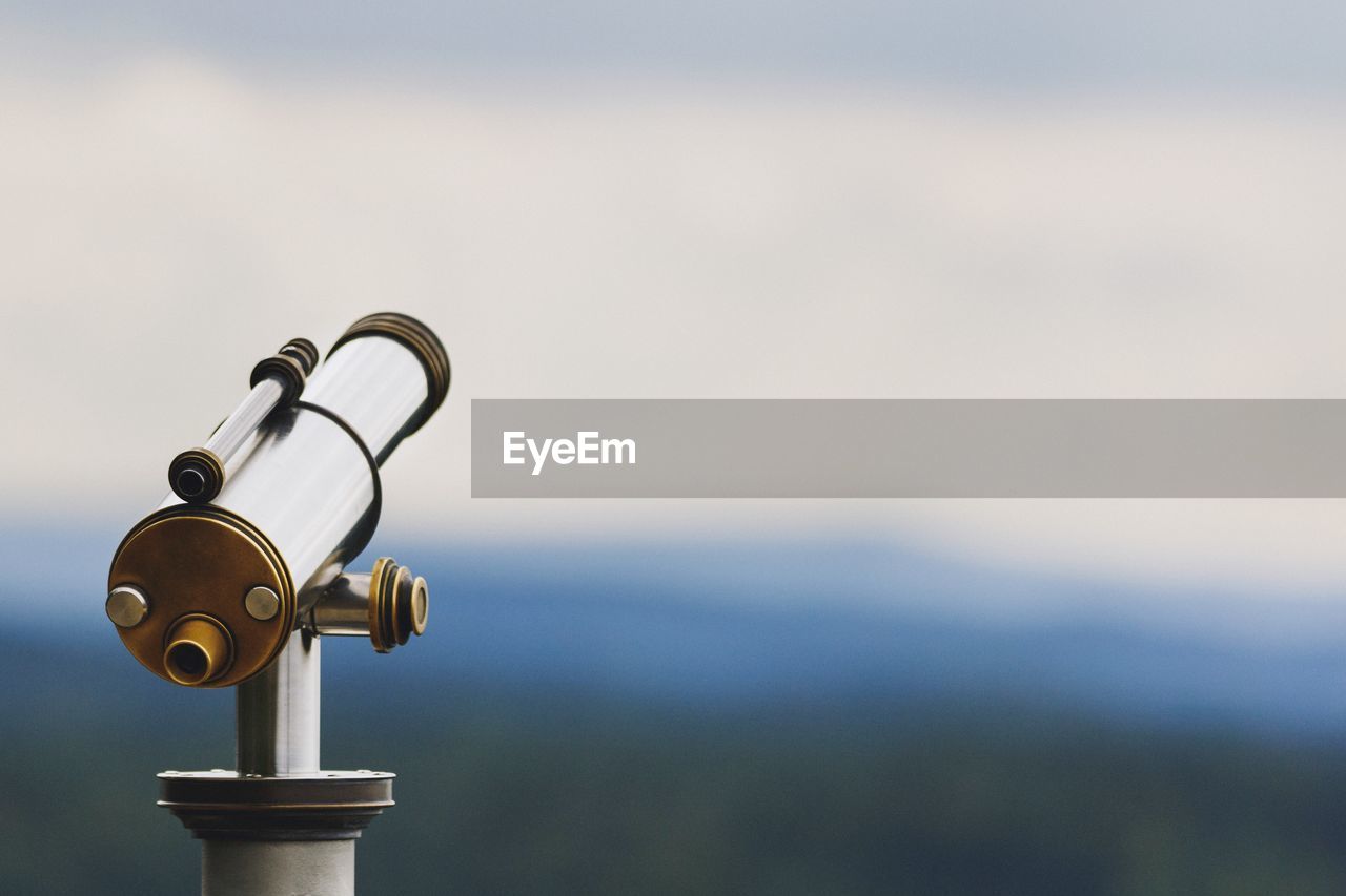 Close-up of hand-held telescope against sky