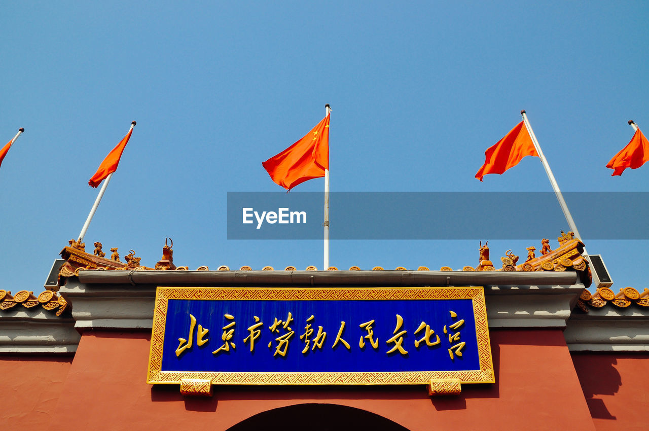 Low angle view of orange flags on pagoda against clear sky