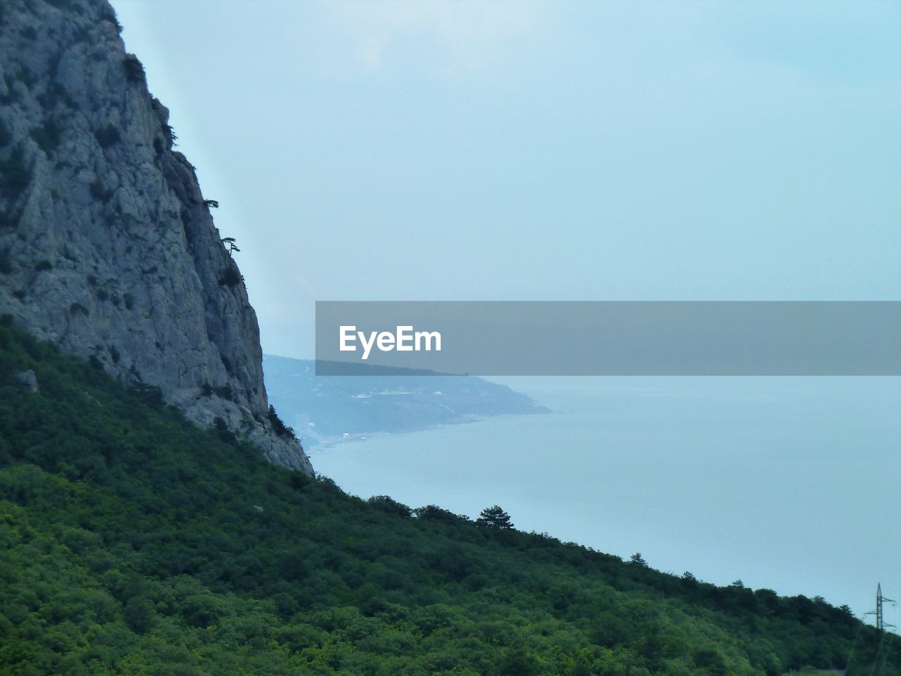 Scenic view of mountain by sea against sky