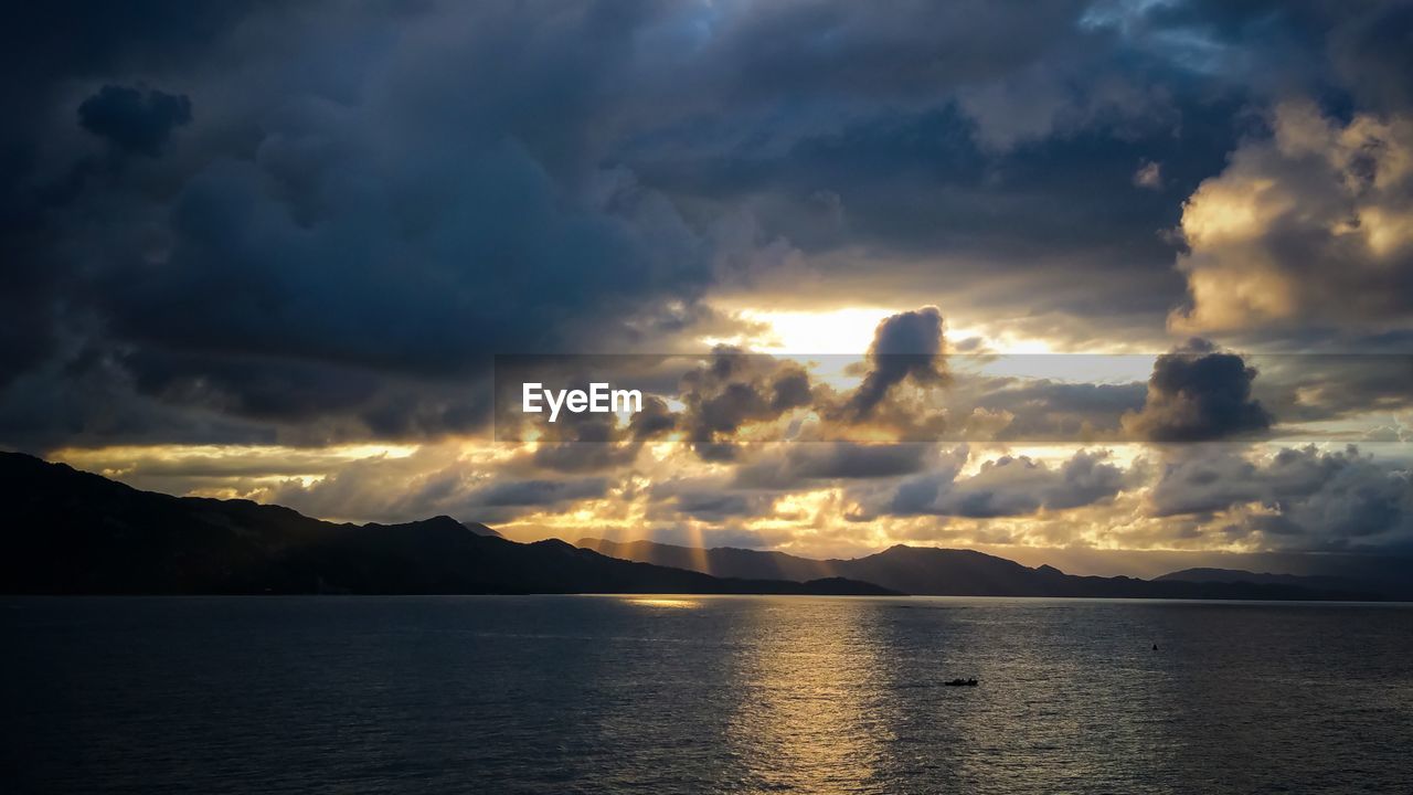 Scenic view of sea against dramatic sky during sunset