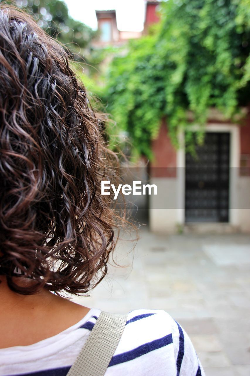 Rear view of woman with curly hair against tree