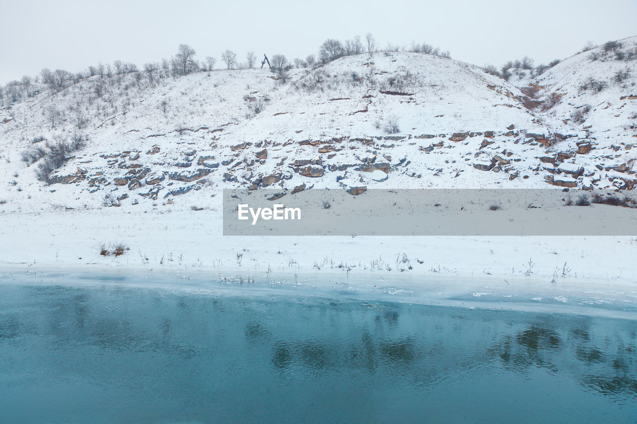 Hill covered by snow and frozen lake . winter frost scenery